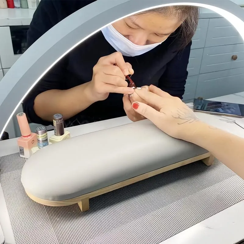Nail technician working under a half moon LED lamp in a salon